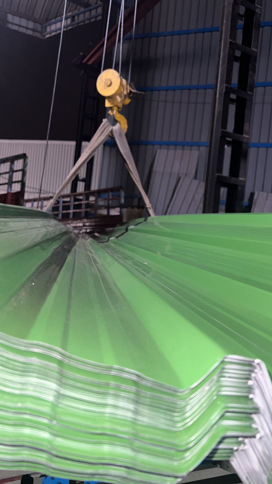 Crane lifting stack of color-coated roofing sheets